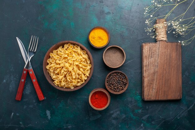 Bovenaanzicht rauwe Italiaanse pasta met kruiden op donkerblauwe achtergrond ingrediënt voedsel maaltijd rauw