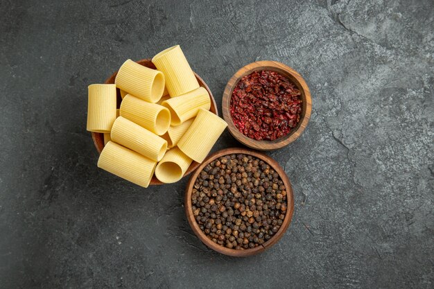 Bovenaanzicht rauwe italiaanse pasta met kruiderijen op de grijze achtergrond pasta deeg maaltijd rauw pittig