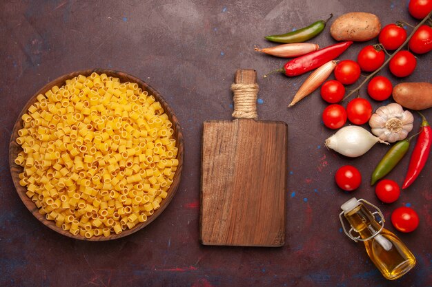 Bovenaanzicht rauwe Italiaanse pasta met verse groenten op de donkere achtergrond plantaardige pasta maaltijd voedselkleur