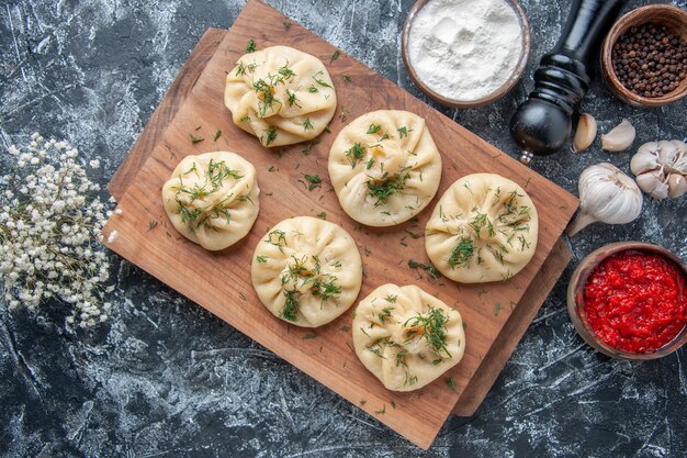 Bovenaanzicht rauwe kleine knoedels met vlees en tomatensaus op grijs oppervlak deeg maaltijd cake taart keuken schotel vlees koken