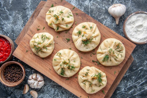 Bovenaanzicht rauwe kleine knoedels met vlees en tomatensaus op het grijze oppervlak deeg hotcake keuken maaltijd cake taart koken