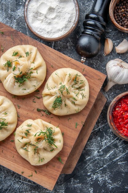 Bovenaanzicht rauwe kleine knoedels met vlees en tomatensaus op het grijze oppervlak deeg maaltijd cake taart keuken gerecht diner vlees koken