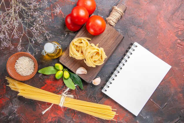 Bovenaanzicht rauwe pasta met olietomaten en knoflook op donkere oppervlak deeg rauwe pasta