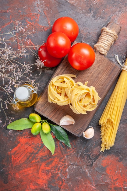 Bovenaanzicht rauwe pasta met olietomaten en knoflook op donkere vloer rauw pastadeeg