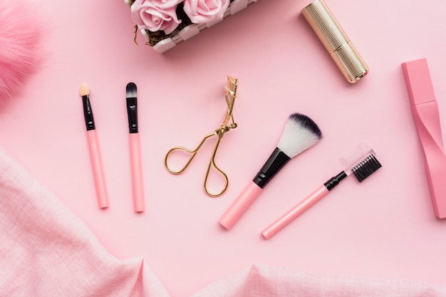 Bovenaanzicht regeling met make-up borstels op roze achtergrond