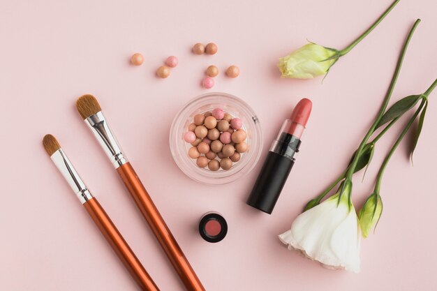 Bovenaanzicht regeling met make-up producten en roze achtergrond