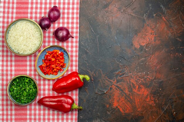 Bovenaanzicht rijst in een kom rode paprika rode uien kommen met gesneden tomaten en groen op donkere tafel kopieerruimte