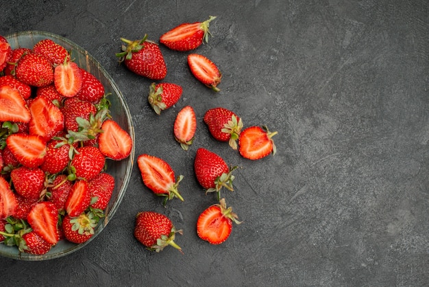 Bovenaanzicht rode aardbeien gesneden en hele vruchten op grijze achtergrond