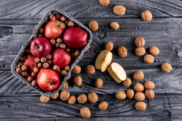 Bovenaanzicht rode appels in de mand met noten en walnoten op grijze houten horizontale 1