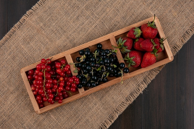 Gratis foto bovenaanzicht rode en zwarte bessen met aardbeien op een houten achtergrond