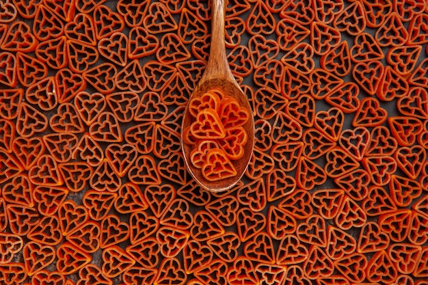 Gratis foto bovenaanzicht rode harten italiaanse pasta op lepel en op donkere tafel
