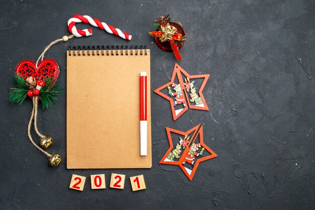 Bovenaanzicht rode markering op notebook staande in een cirkel van verschillende kerstversieringen op donkere geïsoleerde oppervlakte vrije ruimte