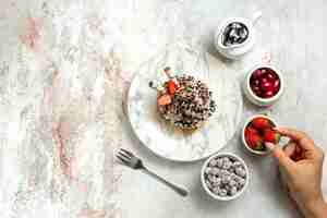 Gratis foto bovenaanzicht romige heerlijke cake met aardbeien en snoepjes op wit oppervlak verjaardag cream tea cake biscuit zoete cookie