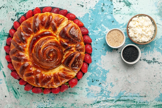 Bovenaanzicht ronde heerlijke taart met verse aardbeien op het blauwe oppervlak