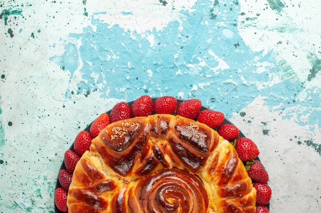 Bovenaanzicht ronde heerlijke taart met verse rode aardbeien op het blauwe oppervlak