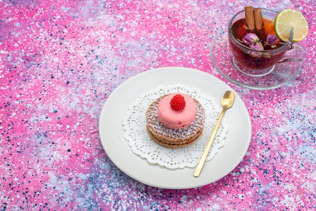 Bovenaanzicht ronde koekje met Franse macarons en thee op de gekleurde backgorund suiker zoete cake kleur