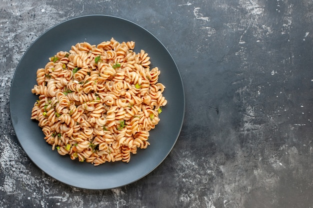 Bovenaanzicht rotini pasta op ronde plaat op donkere ondergrond met vrije ruimte