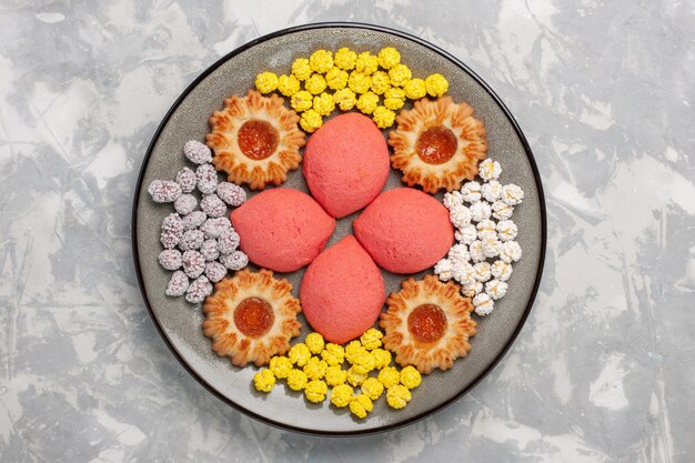 Bovenaanzicht roze taarten met snoepjes en koekjes in plaat op witte ondergrond zoete bak cake biscuit thee taart cookie