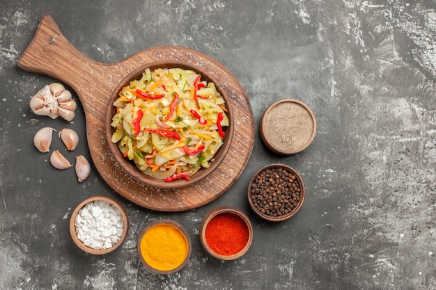 Bovenaanzicht salade knoflook kommen kleurrijke kruiden groente salade op de snijplank