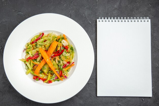 Bovenaanzicht salade plaat van een smakelijke salade met wortelen paprika witte notebook