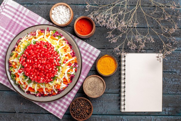 Bovenaanzicht schotel en tafelkleed witte notitieboekjekruiden en boomtakken naast het geruite tafelkleed en bord met eten