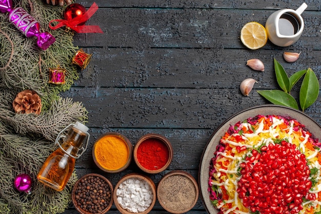 Bovenaanzicht schotel en vuren takken smakelijke kerstschotel met citroenfles olie en kruiden naast de vuren takken met kegels en knoflook