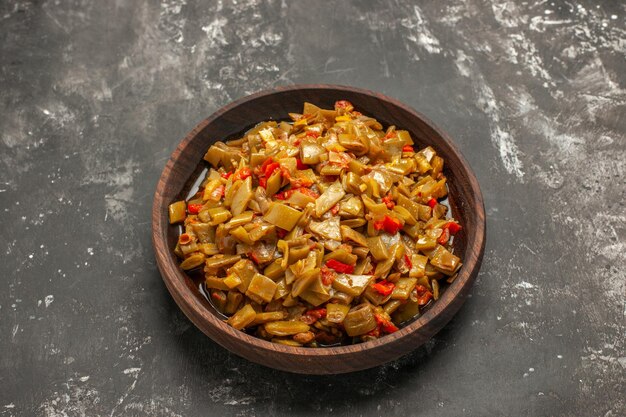 Bovenaanzicht schotel op de tafelkom met sperziebonen met tomaten op de donkere tafel