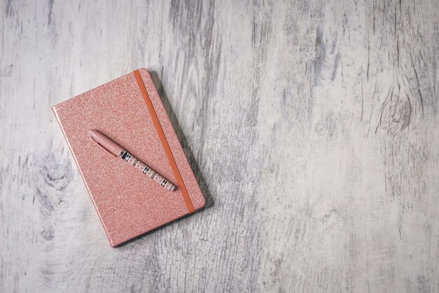 Bovenaanzicht shot van een met glitter bedekt notitieboekje met pen op de grijze houten achtergrond met kopieerruimte