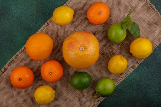 Bovenaanzicht sinaasappelen met grapefruit, citroenen en limoenen (lemmetjes) op een beige servet