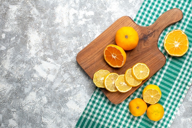Bovenaanzicht sinaasappels citroen schijfjes op snijplank citroenen op groen wit geruit tafelkleed op grijze tafel vrije ruimte