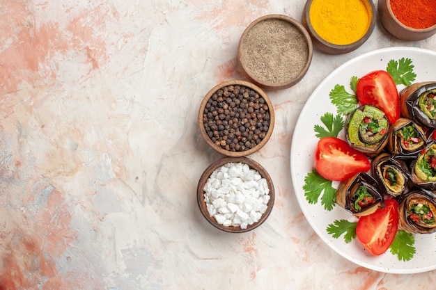 Bovenaanzicht smakelijke auberginerolletjes met groene tomaten en kruiden