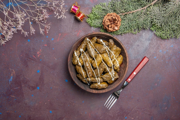 Bovenaanzicht smakelijke blad dolma vleesgerecht binnen bruine plaat op donker