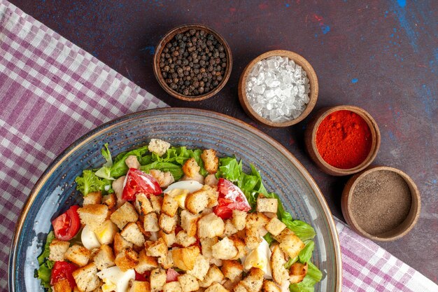 Bovenaanzicht smakelijke caesar salade met kruiden op het donkere bureau