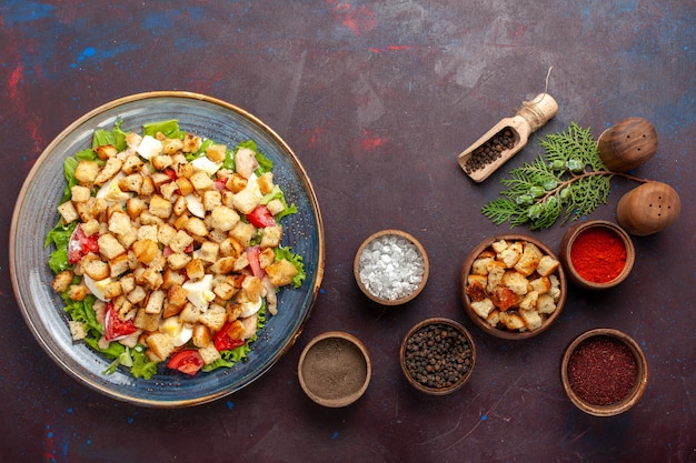 Bovenaanzicht smakelijke caesar salade met verschillende kruiden op donkerpaars bureau