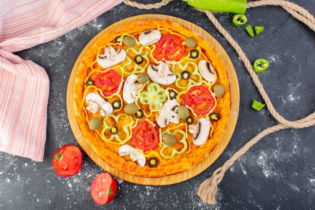 Bovenaanzicht smakelijke champignonpizza met rode tomaten olijven champignons met verse tomaten helemaal over het grijze bureau pizzadeeg italiaans