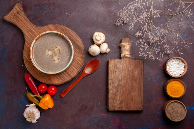 Bovenaanzicht smakelijke champignonsoep met verschillende kruiden op het donkere bureau soep champignons kruiden voedsel maaltijd