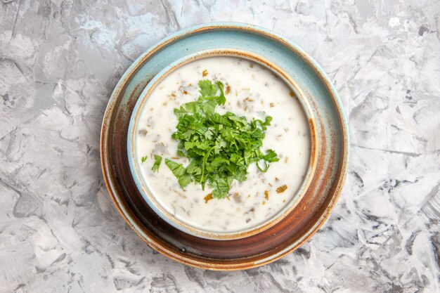 Bovenaanzicht smakelijke dovga yoghurtsoep met greens in plaat op witte tafel melksoepmaaltijd