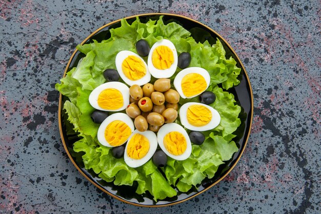 bovenaanzicht smakelijke eiersalade bestaat uit groene salade en olijven op lichte achtergrond