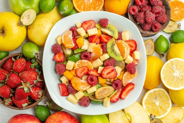 Bovenaanzicht smakelijke fruitsalade met verschillende vruchten op een witte achtergrond