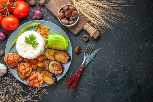 Bovenaanzicht smakelijke gebakken aubergines met gekookte rijst en rozijnen op donkere achtergrond