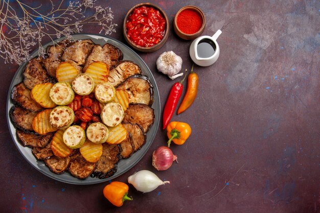 Bovenaanzicht smakelijke gebakken groenten aardappelen en aubergines op de donkere achtergrond maaltijd oven koken bakken groenten