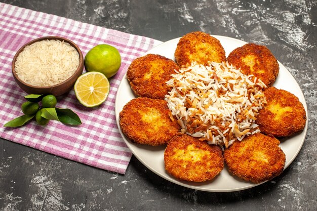 Bovenaanzicht smakelijke gebakken schnitzels met gekookte rijst op donkere bureau rissole vlees eten