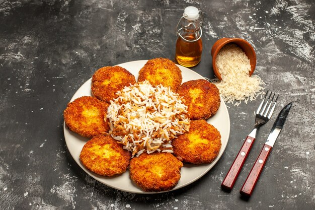 Bovenaanzicht smakelijke gebakken schnitzels met gekookte rijst op donkere oppervlak gerecht maaltijd foto