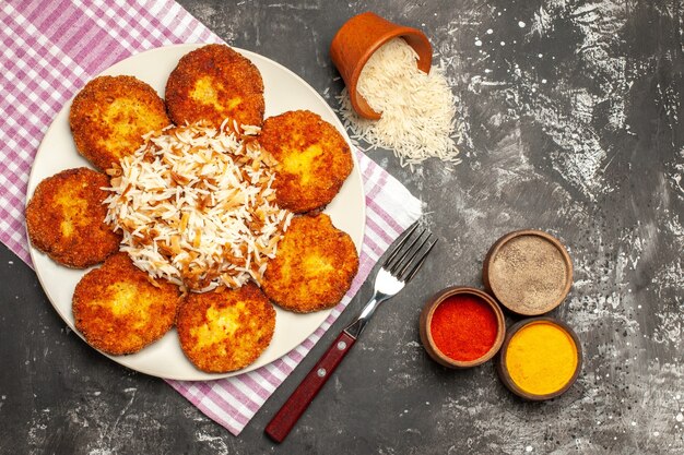 Bovenaanzicht smakelijke gebakken schnitzels met gekookte rijst op donkere vloer rissole vleesgerecht