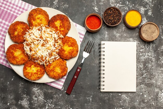 Bovenaanzicht smakelijke gebakken schnitzels met rijst en kruiden op het donkere oppervlak vlees rissole eten