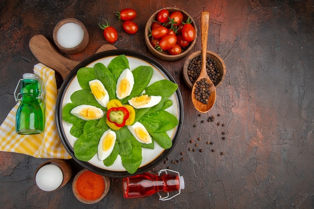 Bovenaanzicht smakelijke gekookte eieren met kruiden en tomaten op donkere tafel