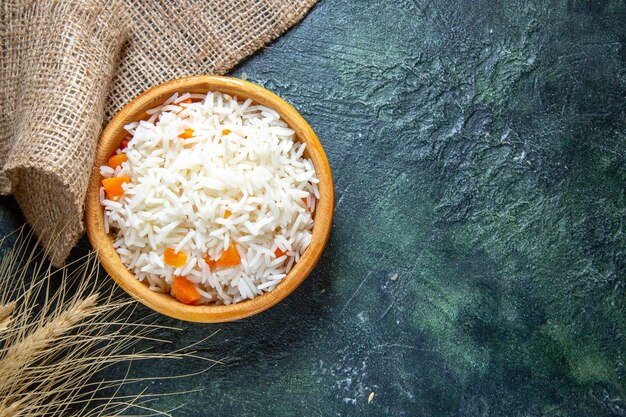 Bovenaanzicht smakelijke gekookte rijst in plaatje op donker bureau