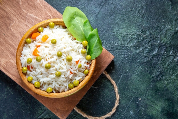 Bovenaanzicht smakelijke gekookte rijst met sperziebonen in plaat op donker bureau