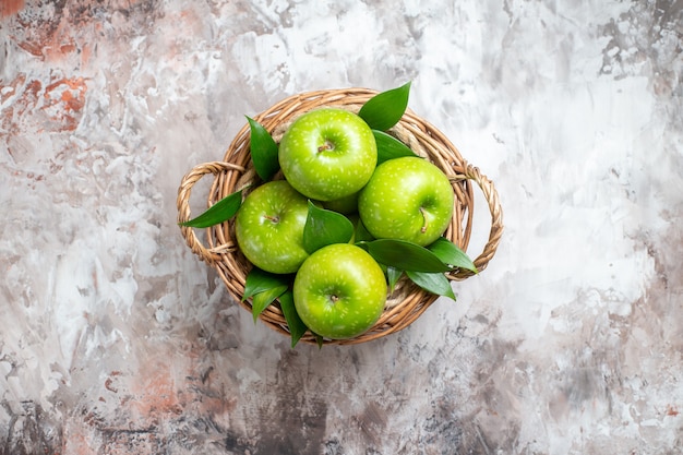 Bovenaanzicht smakelijke groene appels in mand op de lichte achtergrond