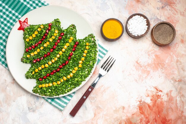 Bovenaanzicht smakelijke groene salade in de vorm van de nieuwe jaarboom met kruiden op lichte achtergrond